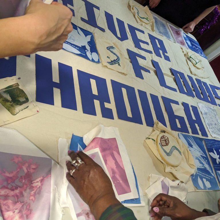 Community Art Group Photo of a pile of artwork, including a drawing of a rubix cube, colourful cut-out geometric shapes, and paperchain made of the same shapes